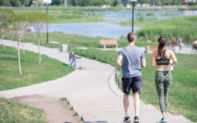 Back view portrait of modern young couple running together outdoors in city park, copy space