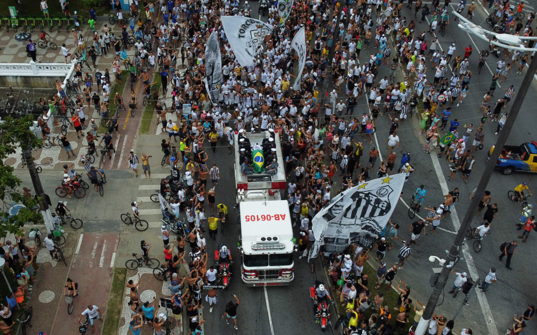 In this aerial picture fans of the late Brazilian football star Pele gather on the street as a firetruck transports Pele's coffin to the Santos' Memorial Cemetery in Santos, Sao Paulo state, Brazil on January 3, 2023.