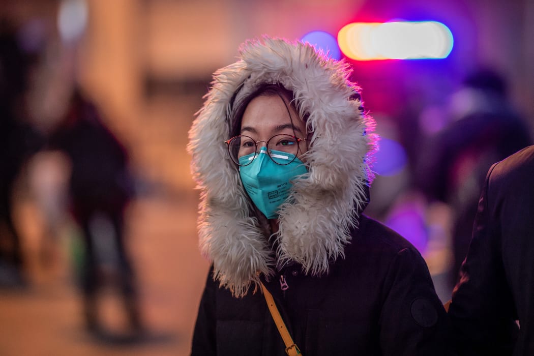 A woman wearing a protective mask walks on the street outside Beijing railway station on January 22, 2020.