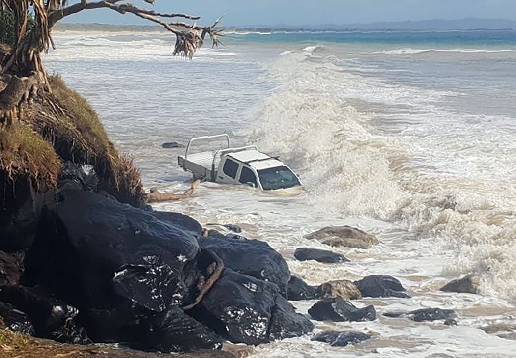 A vehicle at Rainbow Beach swamped by waves in a large swell created by Cyclone Oma.