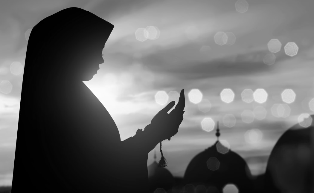 Silhouette of Muslim woman praying .