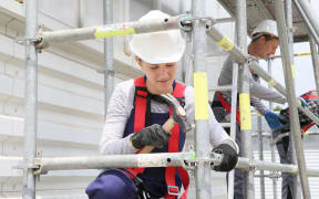 Young woman in professional training working on scaffolding, construction.