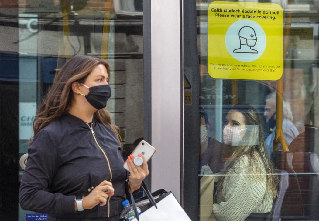 A woman wearing a face mask or covering due to the COVID-19 pandemic, exits a tram in Dublin on September 18, 2020,