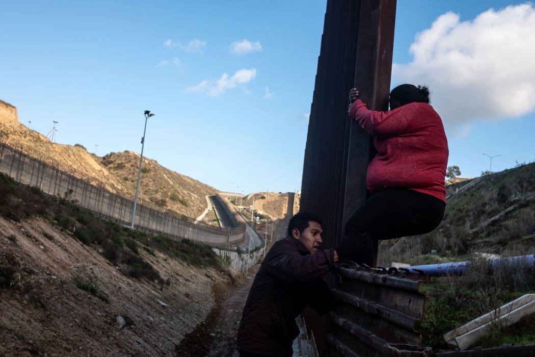 Central American migrants, who have been travelling in a caravan hoping to get to the United States, cross the US-Mexico border fence from Tijuana to San Diego County as seen from Tijuana, Baja California State, Mexico, on December 27, 2018.