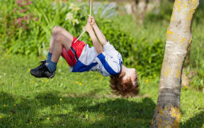 Little boy on a swing in the park.
