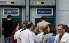People queue at an ATM outside a National bank branch in a suburb of Athens.