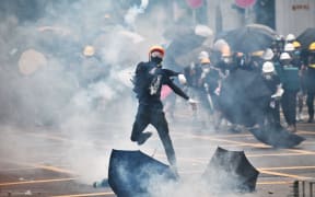 A protester throws tear gas back at police officers during a demonstration in the district of Yuen Long in Hong Kong on July 27, 2019.