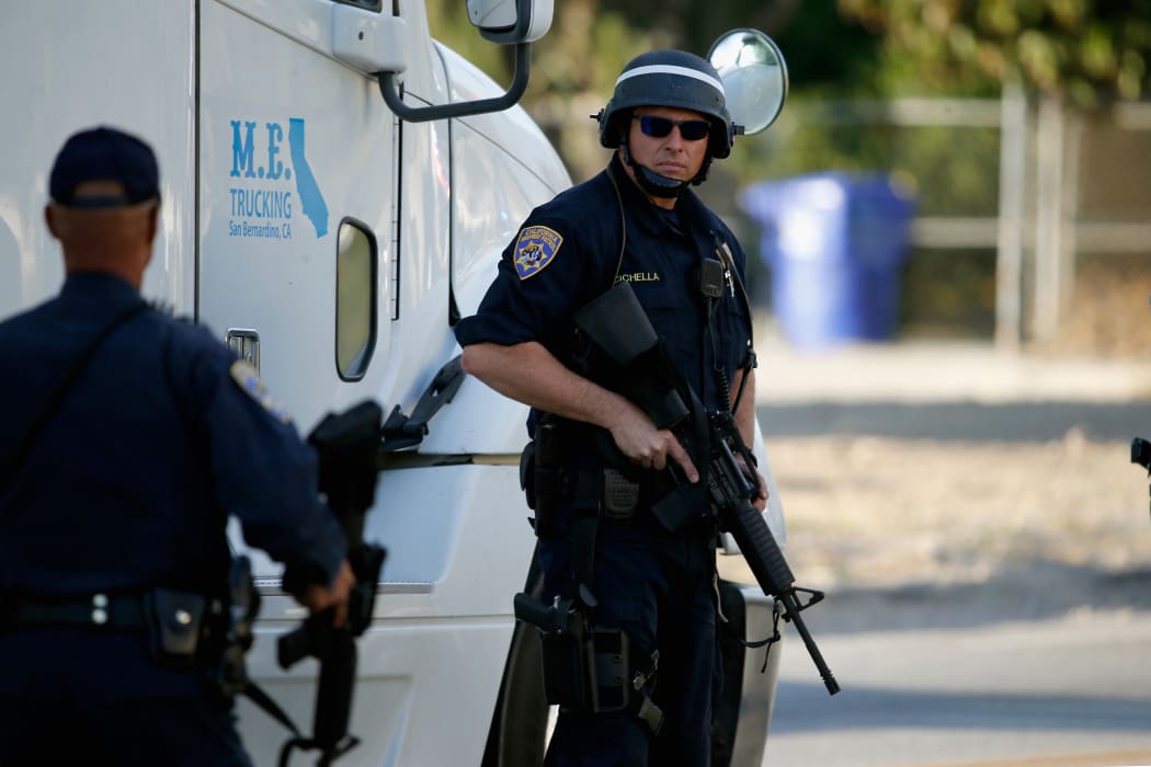 San Bernadino Sheriff officers point weapons into a neighborhood as they pursue suspects of the shooting at the Inland Regional Center on December 2, 2015 in San Bernardino, California.