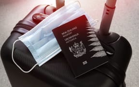 Travelling during covid-19 pandemic. New Zealand passport and protective mask on black suitcase