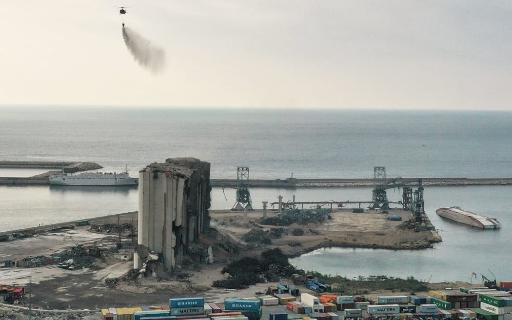 A Lebanese Army helicopter releases water over the heavily damaged grain silos at the port of the capital Beirut, on July 31, 2022, following a partial collapse due to an ongoing fire since the beginning of the month.