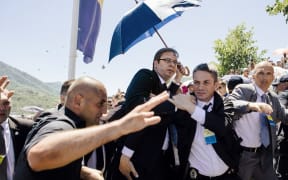 Bodyguards try to protect Serbian Prime Minister Aleksandar Vucic (centre) from stones hurled at him by an angry crowd.