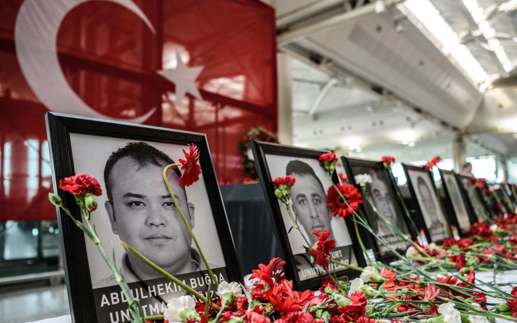 This picture taken on June 30, 2016 shows cloves left by airport employees next to killed airport employees pictures at Ataturk airport international terminal in Istanbul on June 30,