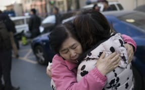 Two relatives of Chinese passengers aboard missing Malaysia Airlines flight MH370 cry as they leave the Beijing Rail Transportation Court in Beijing on March 7, 2016.