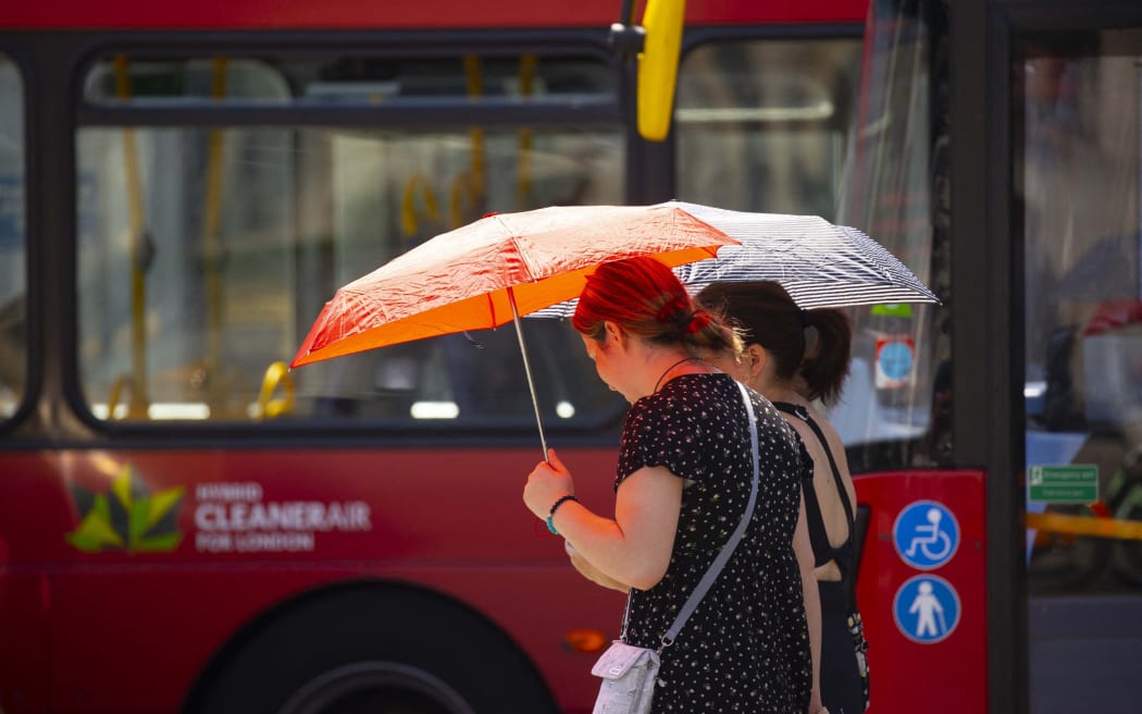 تستخدم النساء المظلات لحماية أنفسهن من أشعة الشمس الحارقة أثناء موجة الحر في لندن.