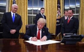 US President Donald Trump signs an executive order as Vice President Mike Pence and Chief of Staff Reince Priebus look on.