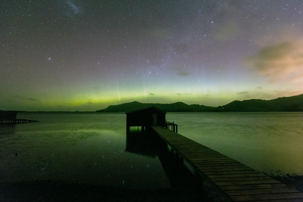 Green aurora, with a silhouetted boat shed in the foreground