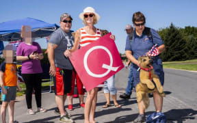 MANKATO, MN - AUGUST 17: Kim Harty (C) holds a Q Anon sign outside Mankato Regional Airport.