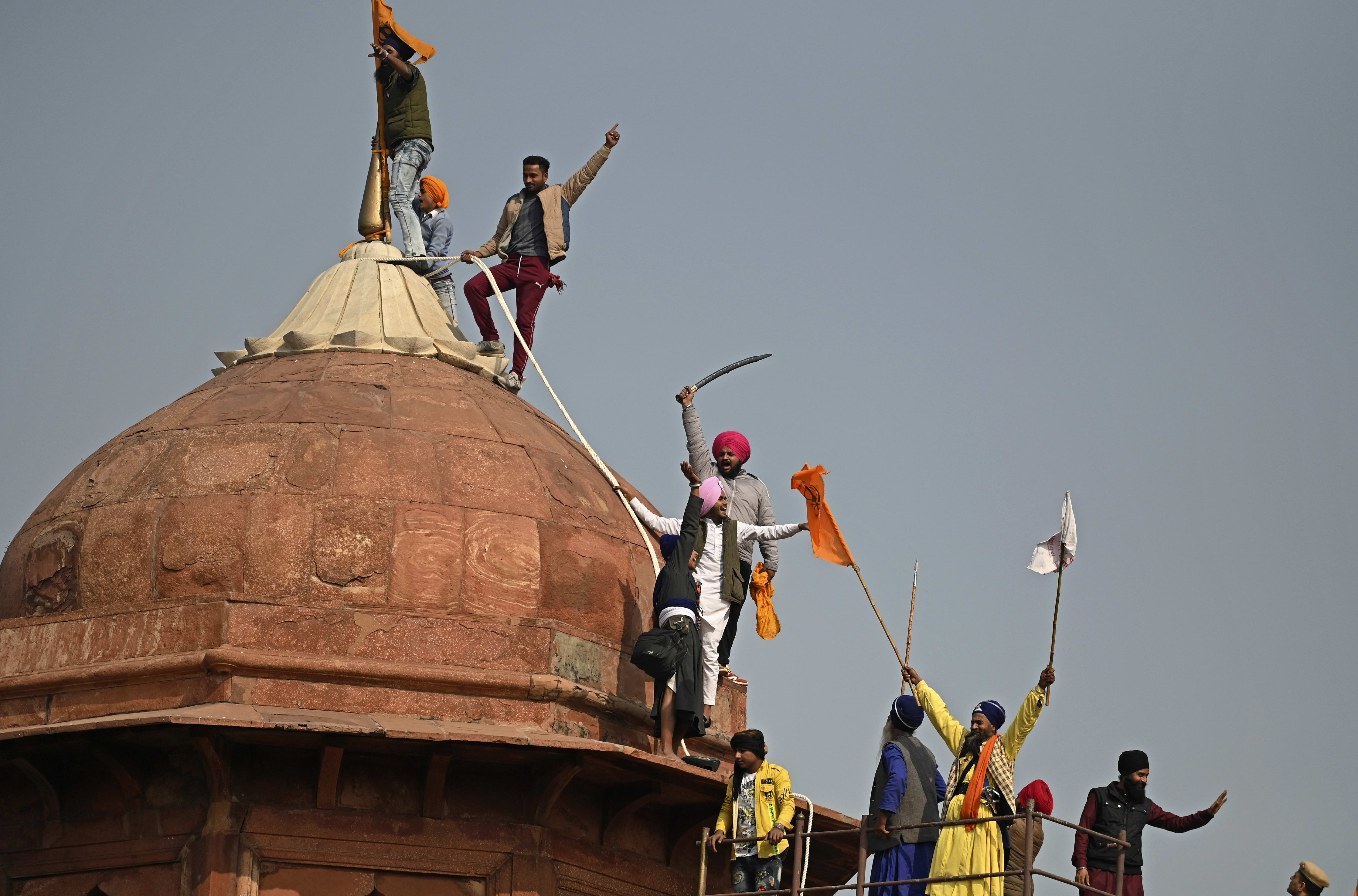 Protesters climb on a dome at the ramparts of the Red Fort as farmers demonstrate against the central government's recent agricultural reforms in New Delhi on January 26, 2021.