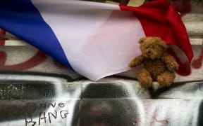 A picture taken on December 2, 2015 in Paris shows a cuddly toy and a French flag at a makeshift memorial in front of the statue of the Republique in tribute to the victims of November 13 terror attacks in Paris.