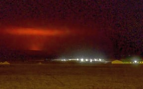 The red shimmer from magma is seen coming out from the erupting Fagradalsfjall volcano behind the town of Keflavik, in Iceland.