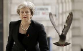FILE - In this Monday, April 23, 2018 file photo a pigeon takes off as Britain's Prime Minister Theresa May arrives