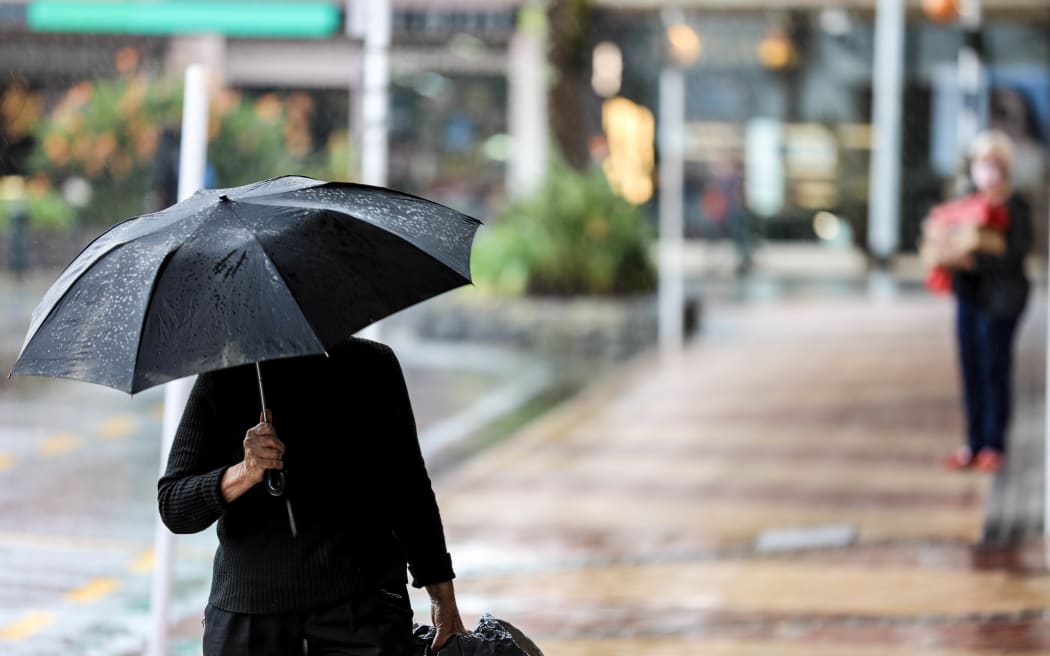 Femme marchant sous la pluie avec un parapluie.
