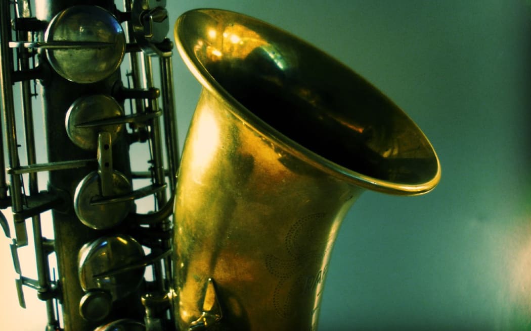 Artistic shot of a tenor saxophone on a blue-green background