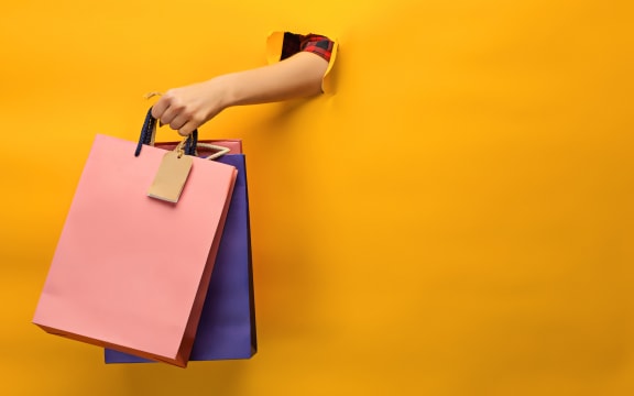 Female hand holding bright shopping bags on yellow