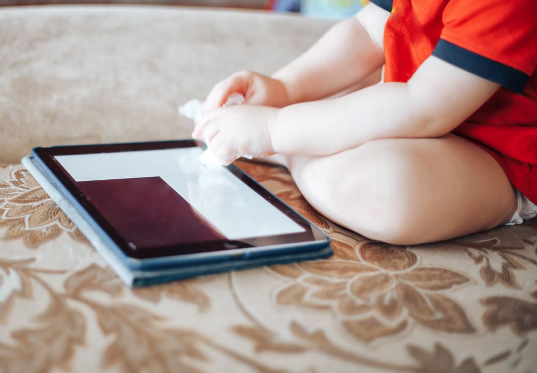 child uses a Tablet PC, hand in focus, without face