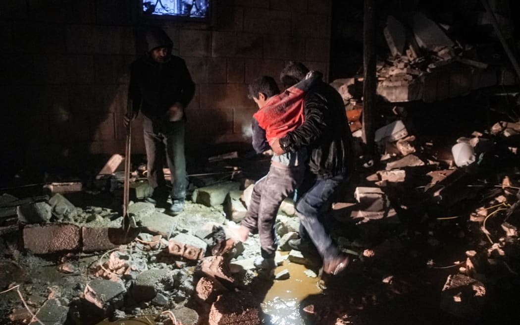 Un homme emporte un enfant blessé à la suite d'un tremblement de terre dans la ville de Jandaris, dans la campagne de la ville d'Afrin, dans le nord-ouest de la Syrie, dans la partie rebelle de la province d'Alep, tôt le 6 février 2023. - Au moins 42 personnes auraient été tuées dans le nord de la Syrie après un tremblement de terre de magnitude 7,8 qui a pris naissance en Turquie et a été ressenti dans les pays voisins.  (Photo de Rami al SAYED / AFP)