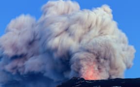 A volcano erupting, with an ash cloud exploding into the air.