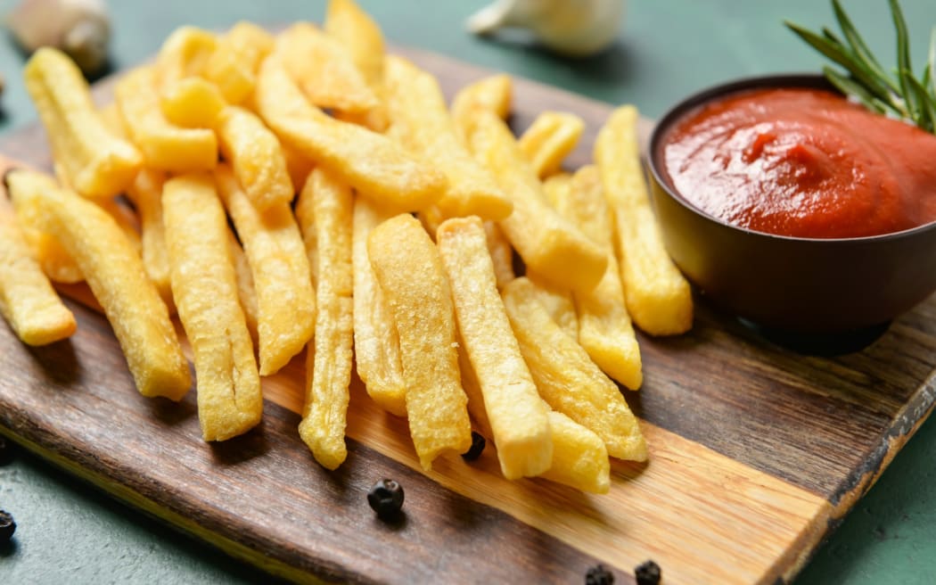 Wooden board with tasty french fries and ketchup on table, closeup