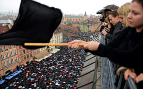 A girl waves a black flag as people take part in a nationwide demonstration to protest against a proposal for a total ban of abortion in Poland.