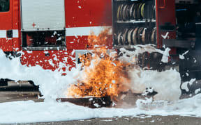 close up view of extinguishing foam, flame and fire truck on street