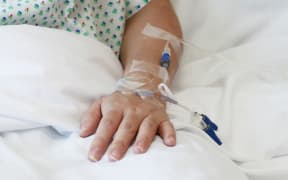 A file photo of a patient in a hospital bed with an IV drip in the arm