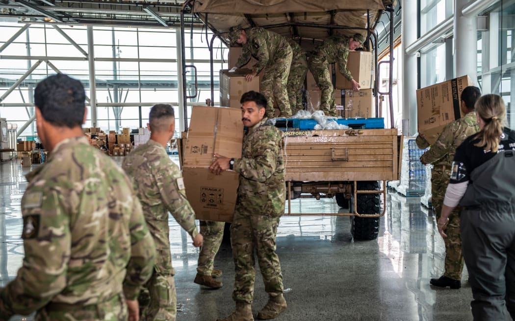 来自第 16 野战团的陆军人员与奥克兰市议会的志愿者一起在奥克兰的中央配送中心卸载物资。 作为 Op Awhina 的一部分，毯子、手电筒和枕头等基本用品将在奥克兰全境分发。