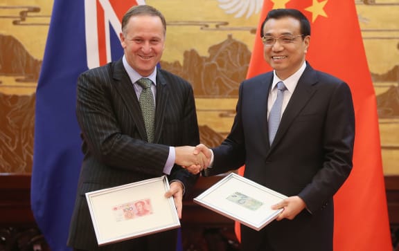 John Key and Chinese Premier Li Keqiang exchange Chinese Yuan and New Zealand Dollar banknotes.