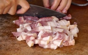 Meat being cut up on chopping board.