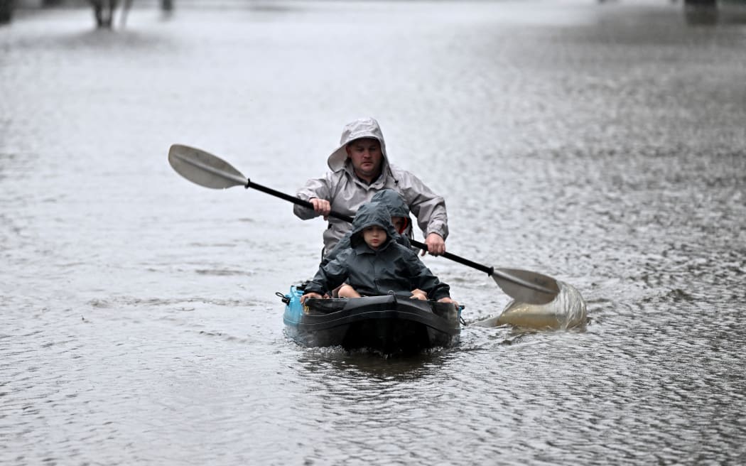People kayak along a flooded street from the overflowing Hawkesbury river due to torrential rain in the Windsor suburb of Sydney on July 4, 2022. (Photo by SAEED KHAN / AFP) (Photo by SAEED KHAN/AFP via Getty Images)
