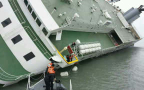 Passengers are helped to safety from the badly listing ferry.
