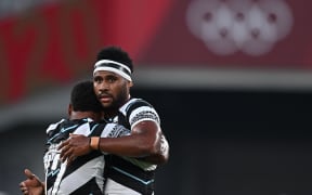 Fiji's Napolioni Bolaca (L) hugs Vilimoni Botitu after winning the men's final rugby sevens match between New Zealand and Fiji during the Tokyo 2020 Olympic Games at the Tokyo Stadium in Tokyo on July 28, 2021. (Photo by Ben STANSALL / AFP)