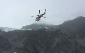 A mountaineer prepares helicopter wreckage for lifting from Fox Glacier.