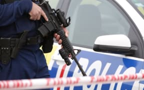 A police officer holds a firearm at the scene of the Hamilton shooting on Tuesday.