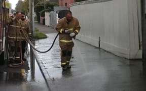 Members of the Fire Brigade hose away remnants of knife-fight in central Christchurch.