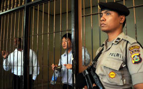 An Indonesian policeman stands guard next to a detention room where Australians Myuran Sukumaran (L) and Andrew Chan (C), members of the so called Bali Nine gang, wait for their trial.