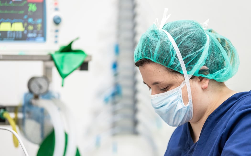 Covid-19 outbreak. Healthcare worker. Nurse working in intensive care unit. Mechanical ventilation system in the background .