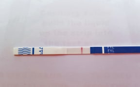 A fentanyl testing strip shows a positive result.