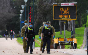 Police officers and soldiers patrol a popular running track in Melbourne on 4 August, 2020 after the state announced new restrictions as the city battles fresh outbreaks of the Covid-19 coronavirus.