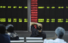 Investors look at screens showing stock market movements at a securities company in Beijing.