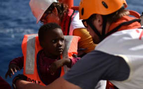 Rescuers take care of a child during a rescue operation at sea of migrants and refugees on May 24, 2016 in the Mediterranean sea in front of the Libyan coast.